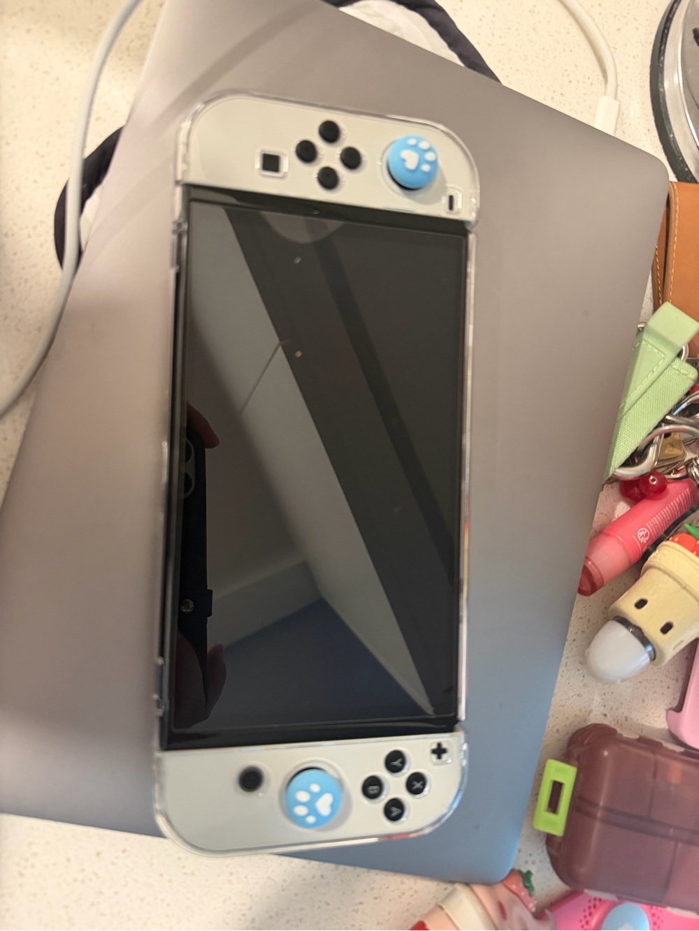 Gray Handheld Gaming Console with Blue Paw Joystick Caps